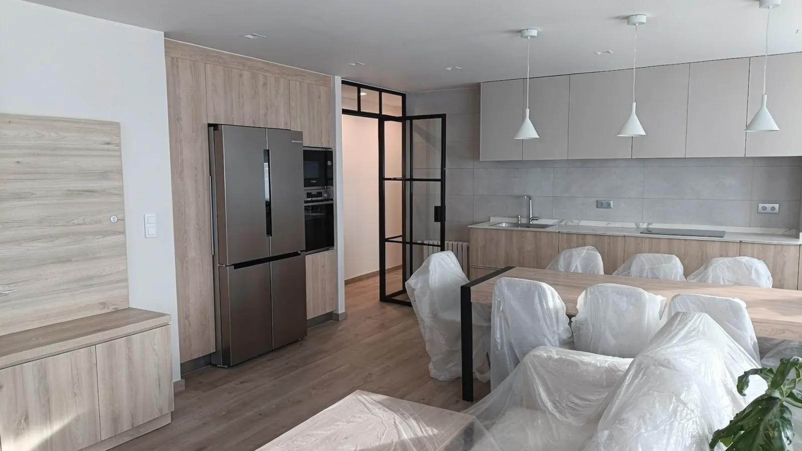 Zona de día con cocina integrada, comedor y salón tras la reforma integral